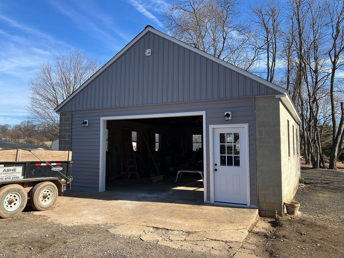 A gray garage with a white door and a truck parked in front of it.