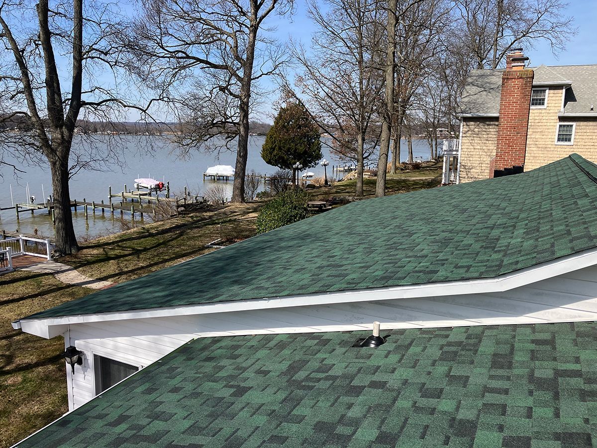A house with a green roof and a view of a lake.