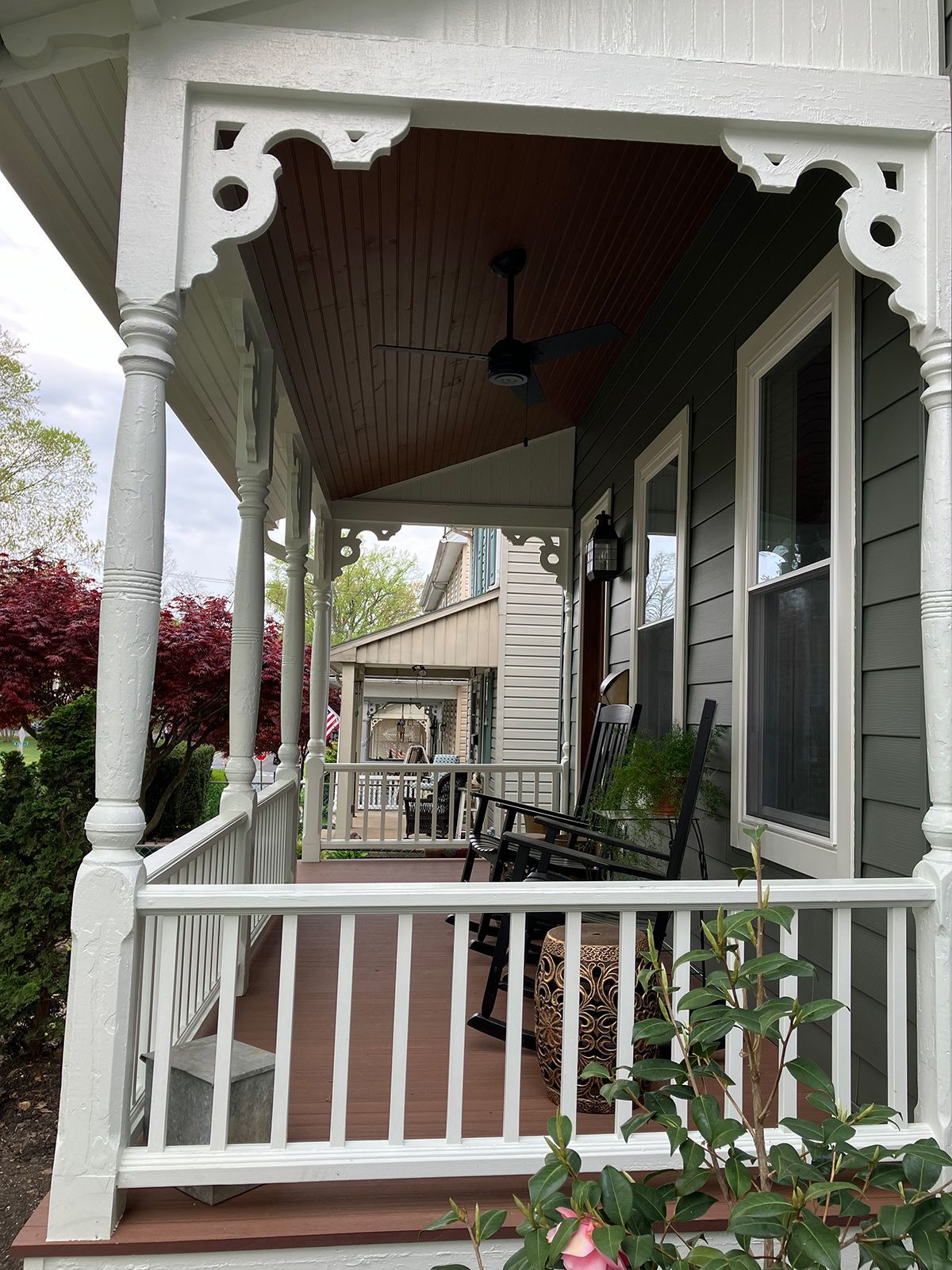 A porch with a chair and a ceiling fan on it.