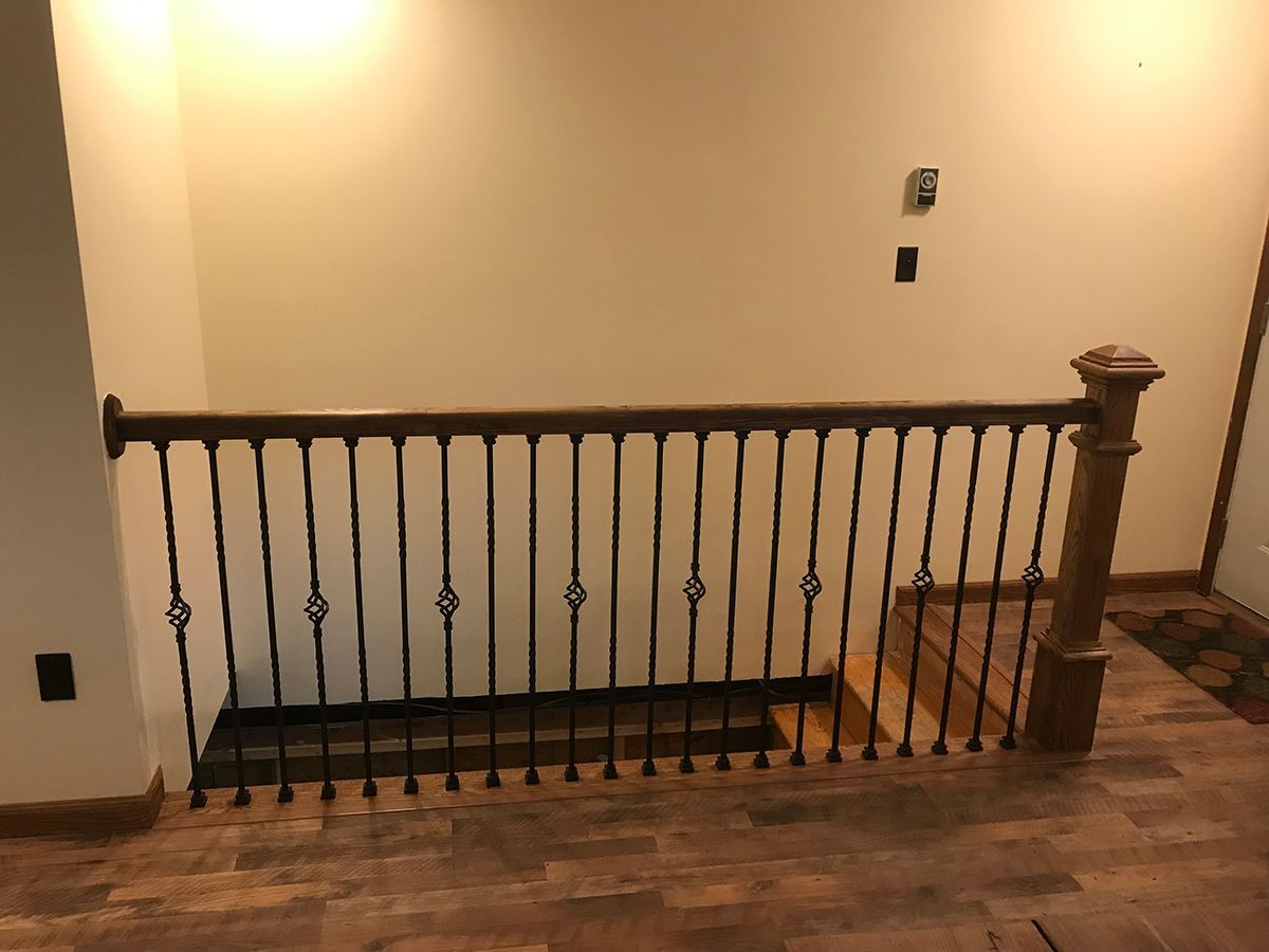 A wooden staircase with a wrought iron railing in a room.