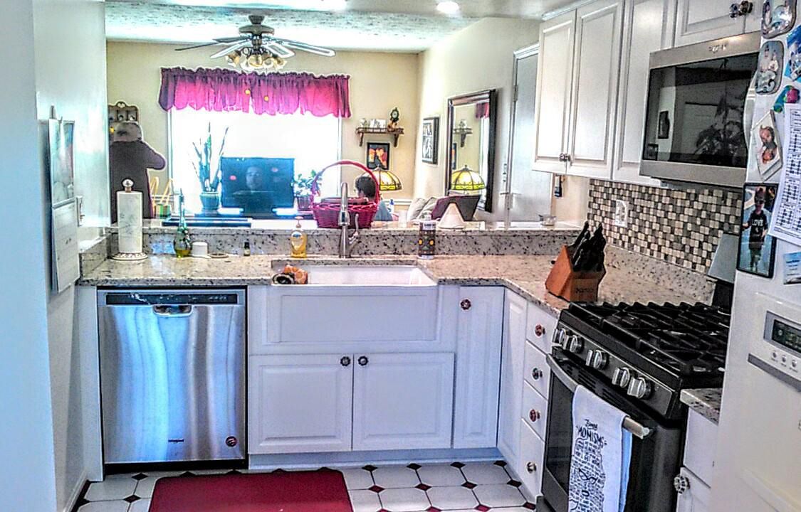 A kitchen with white cabinets , stainless steel appliances , a stove and a sink.