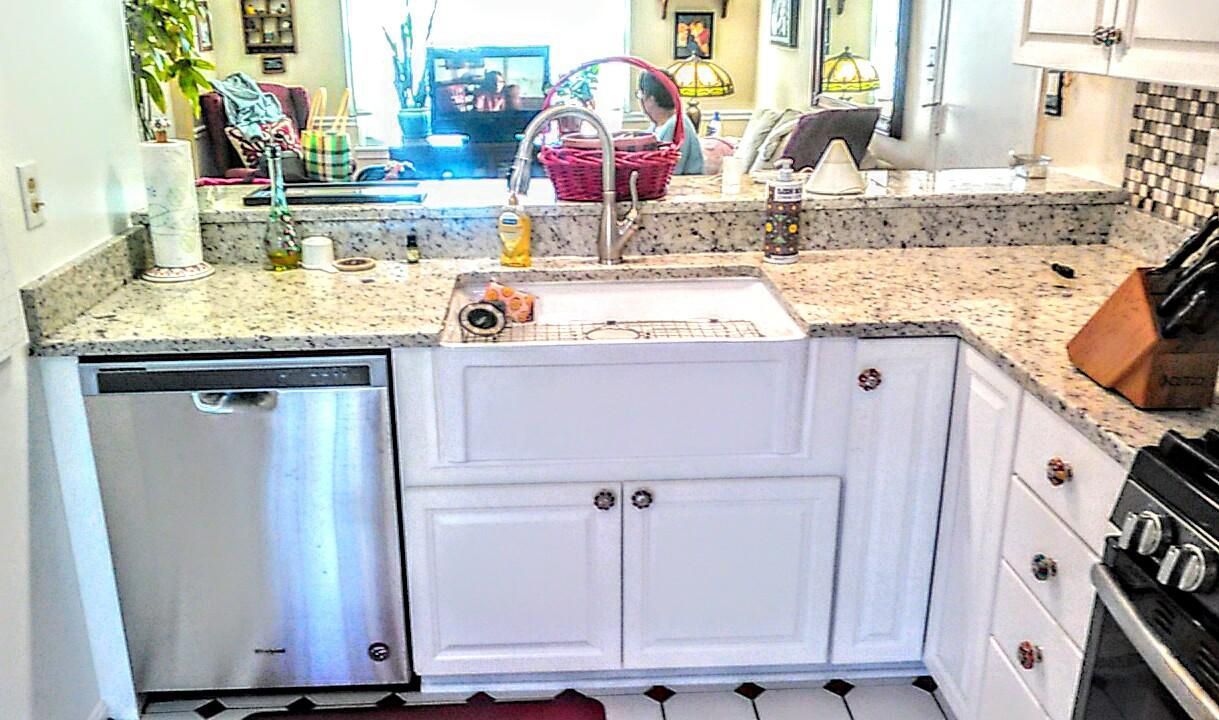A kitchen with white cabinets , granite counter tops , stainless steel appliances and a sink.