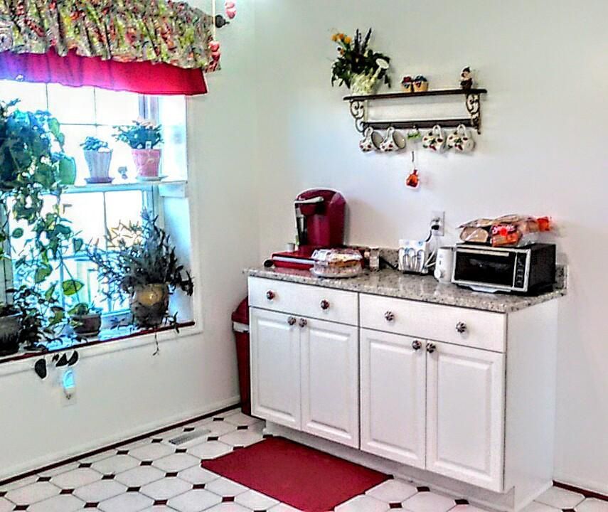 A kitchen with white cabinets , a microwave , and a window.