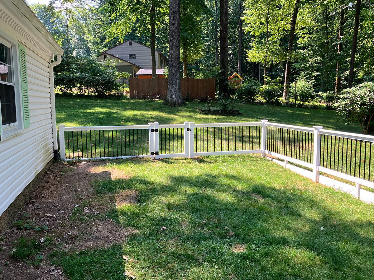 There is a white fence in the backyard of a house.