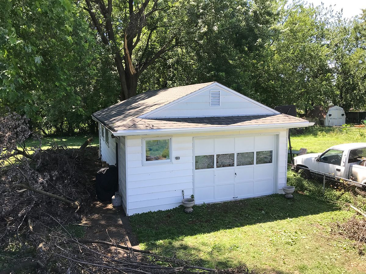 A white garage with a truck parked in front of it.