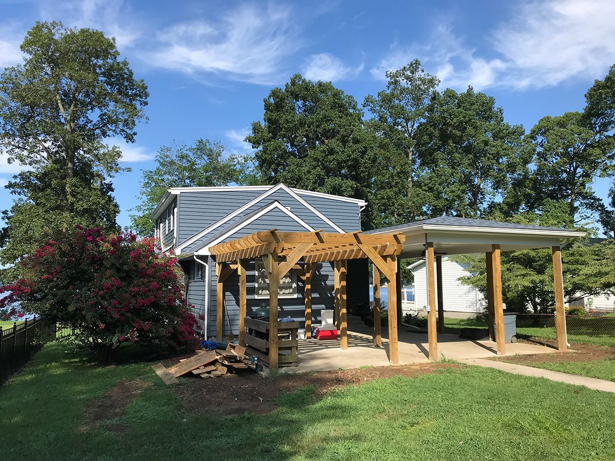 A house with a wooden pergola in front of it.