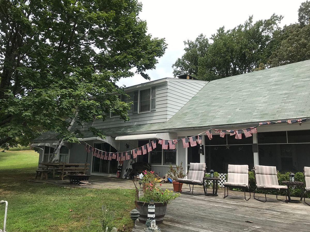 A house with a green roof and a patio decorated with american flags.