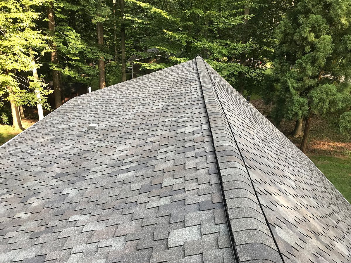 A roof with a lot of shingles on it is surrounded by trees.