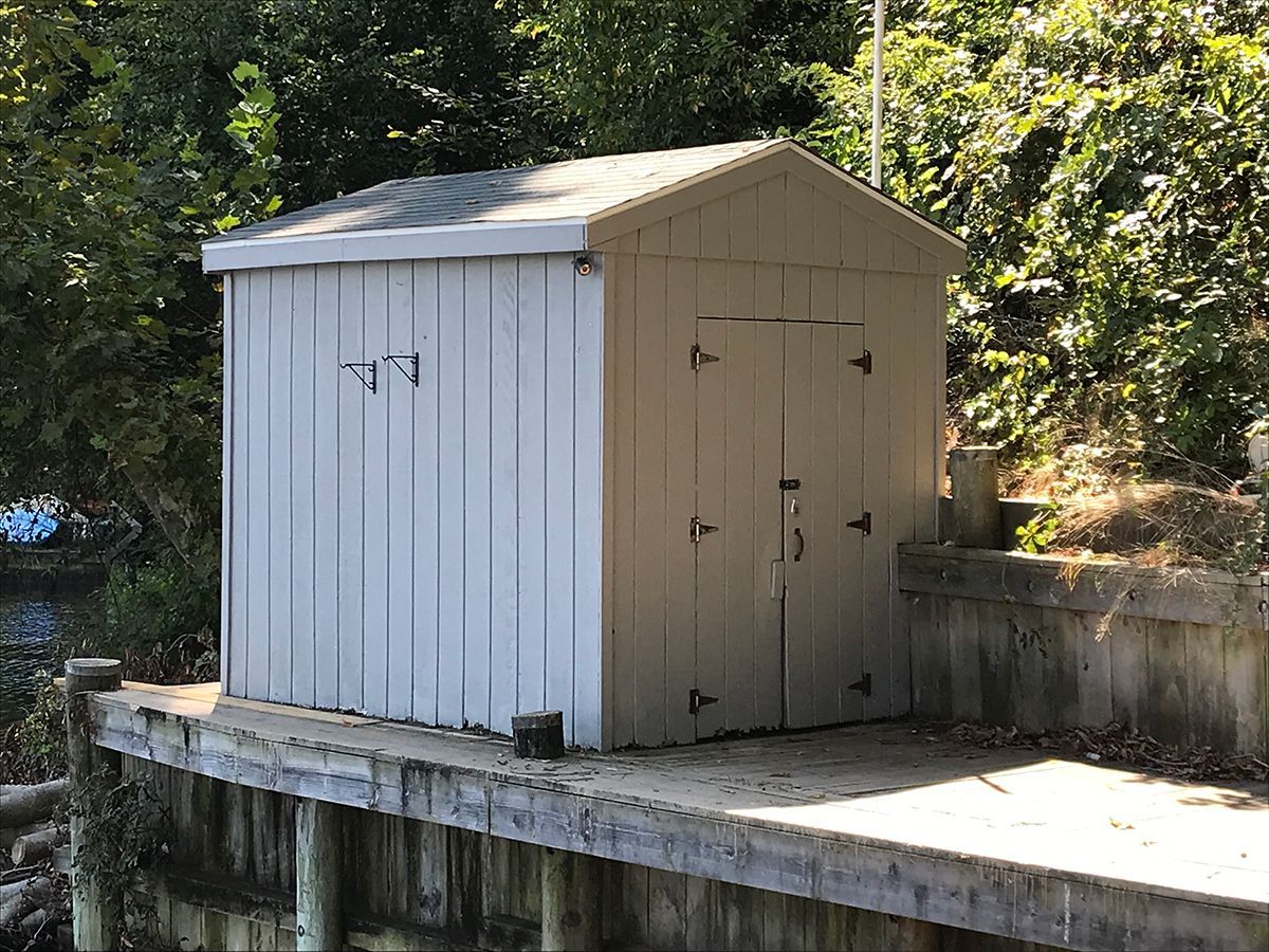 A small shed is sitting on top of a wooden dock.