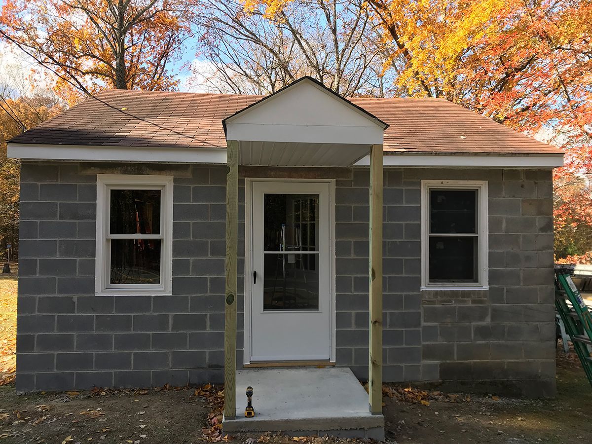 A small brick house with a porch and windows