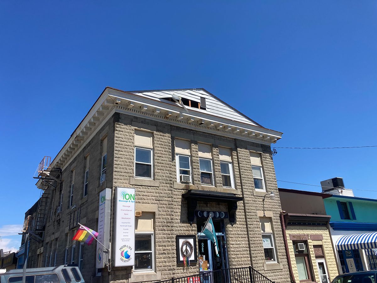 A large brick building with a rainbow flag flying in front of it.