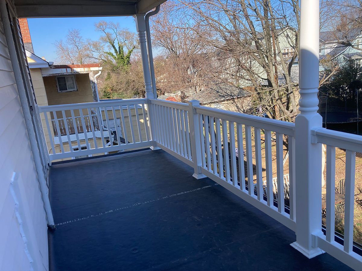 A porch with a white railing and a view of a city.