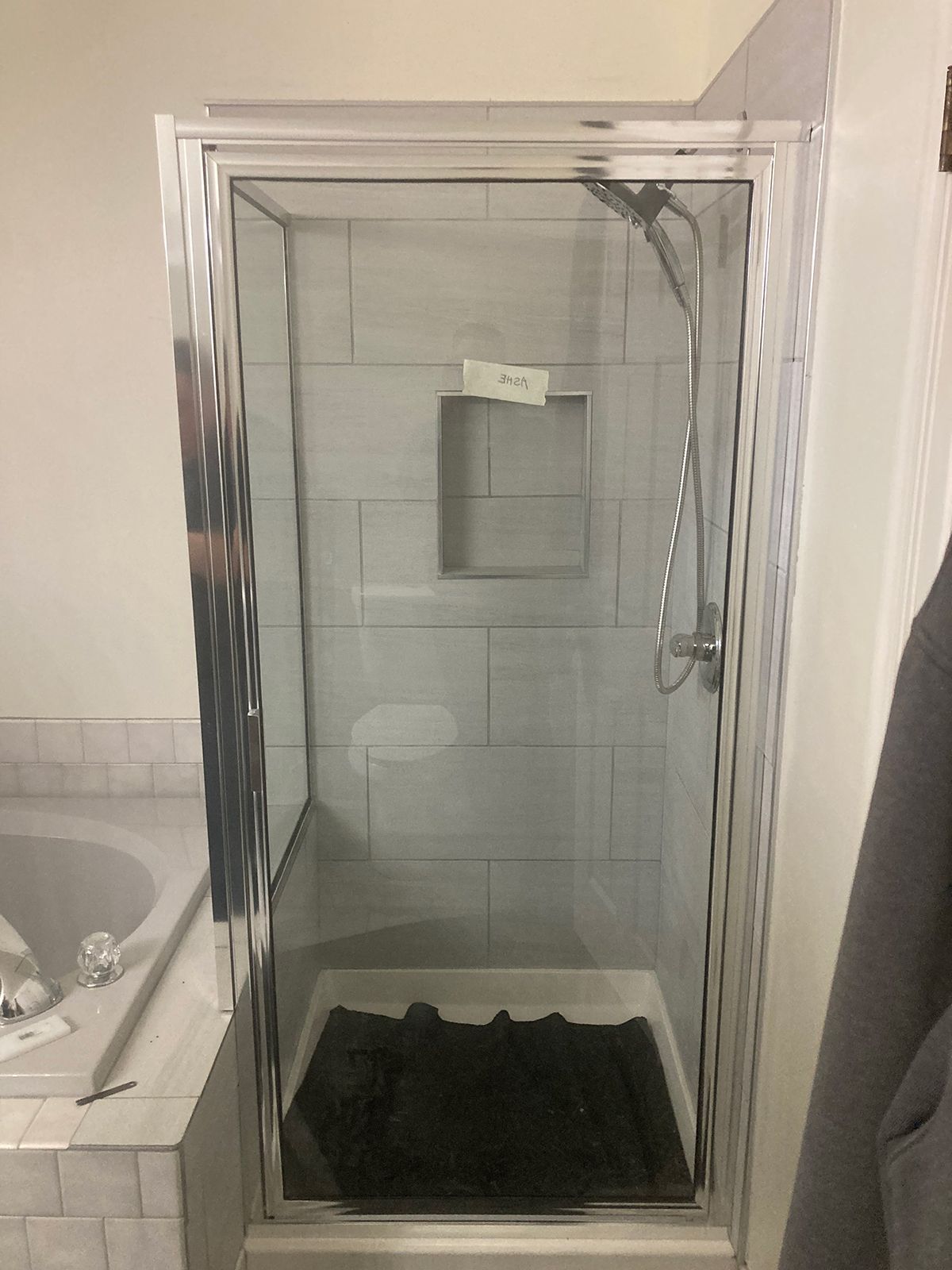 A bathroom with a glass shower door and a bathtub.