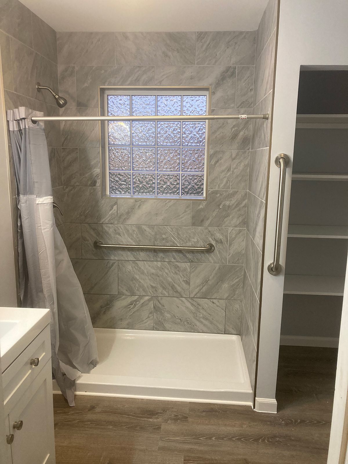A bathroom with a walk in shower and a window.