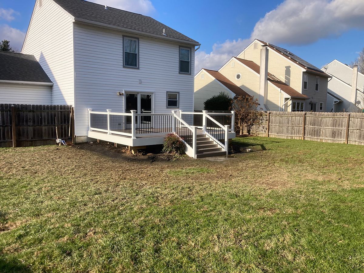A white house with a deck and stairs in the backyard.