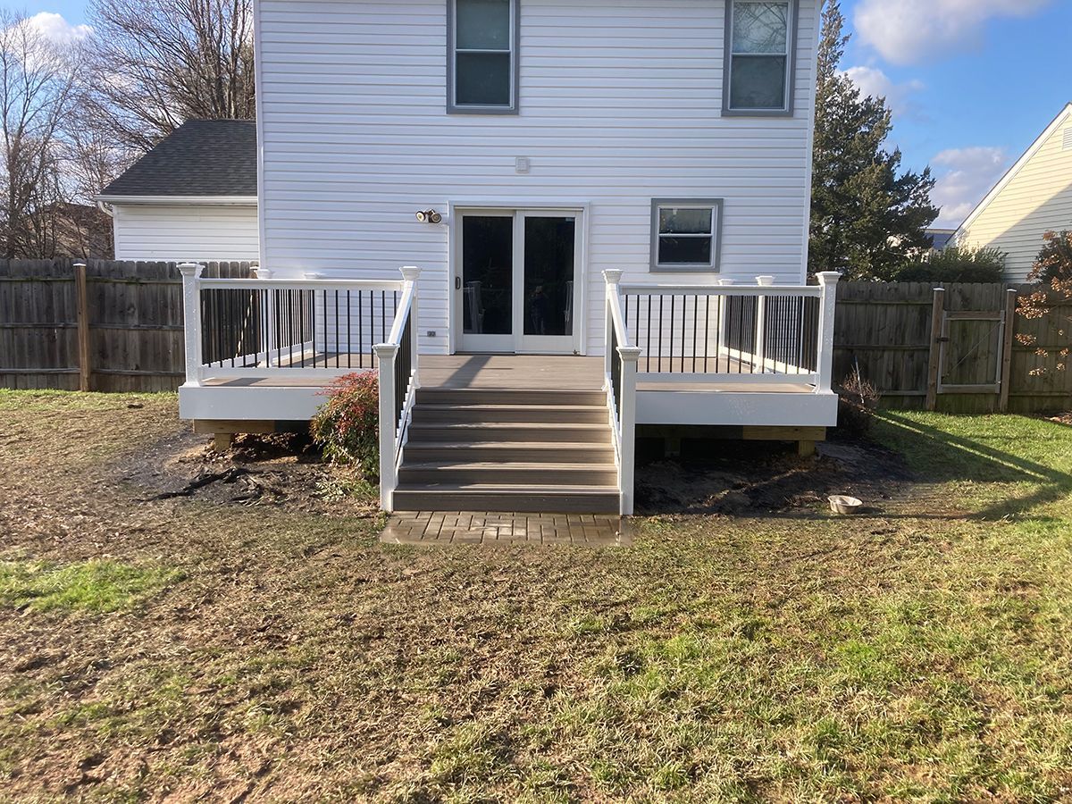 The back of a white house with a deck and stairs.