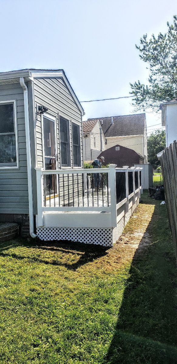 A small house with a porch and a fence in the backyard.