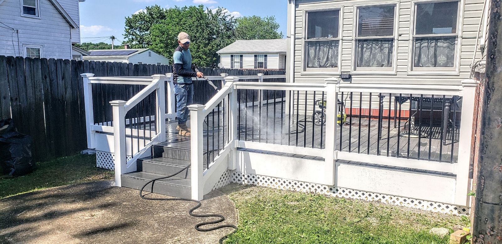 A man is cleaning a deck with a pressure washer.