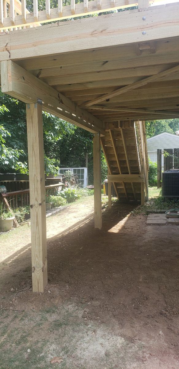 A wooden deck with stairs underneath it is being built.