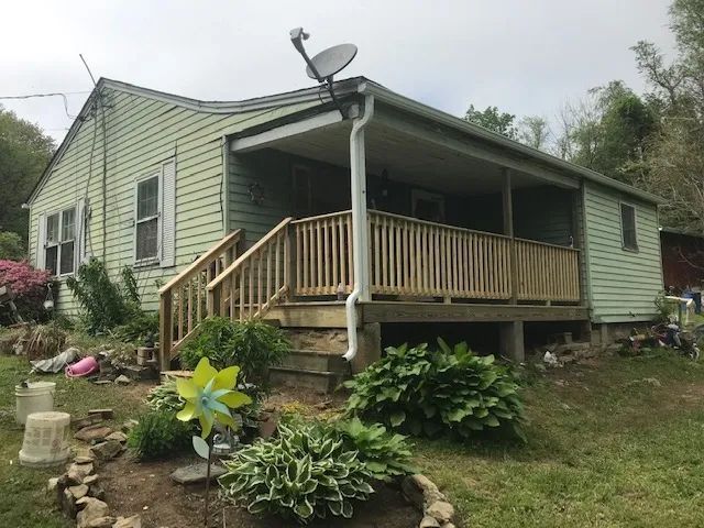 A house with a porch and a satellite dish on the roof