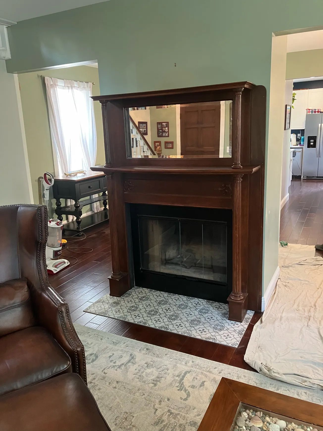 A living room with a fireplace and a mirror above it.