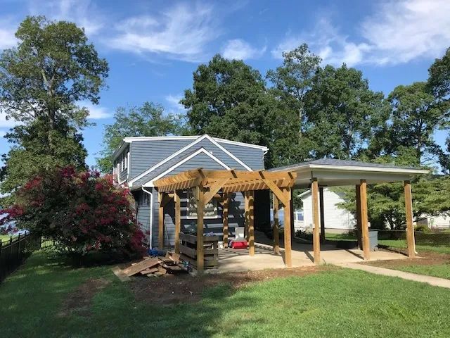 A house with a wooden pergola in front of it.