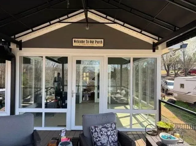 Front porch with white screened windows, black trim, and a small sign above the door