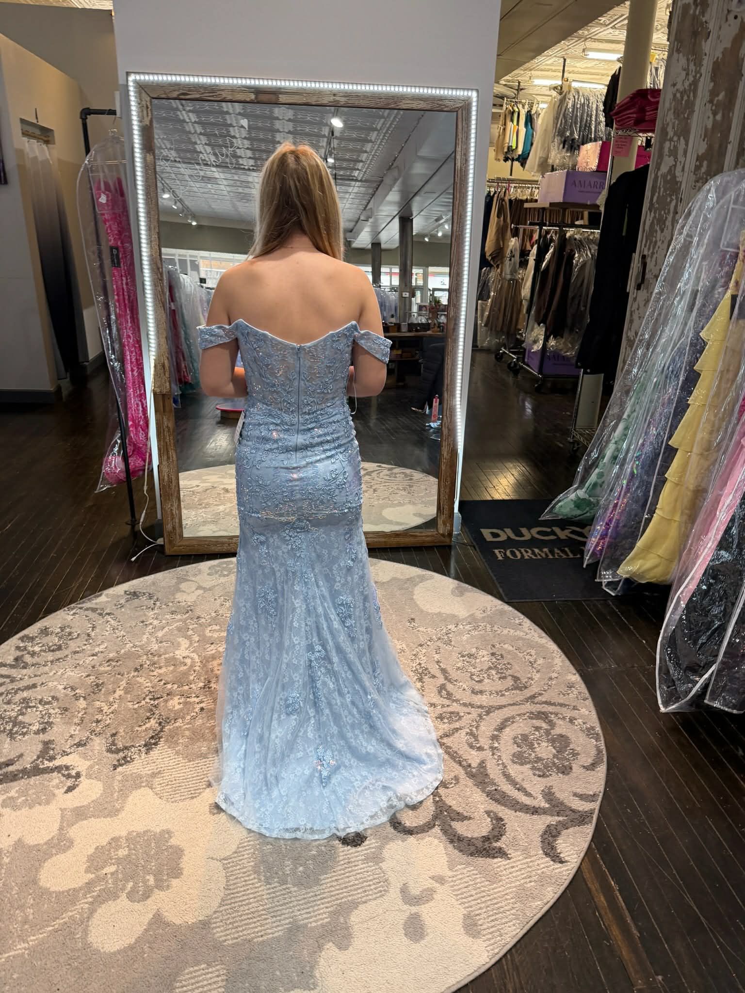 Nine people in formal black and orange evening gowns stand in a row in a clothing boutique.