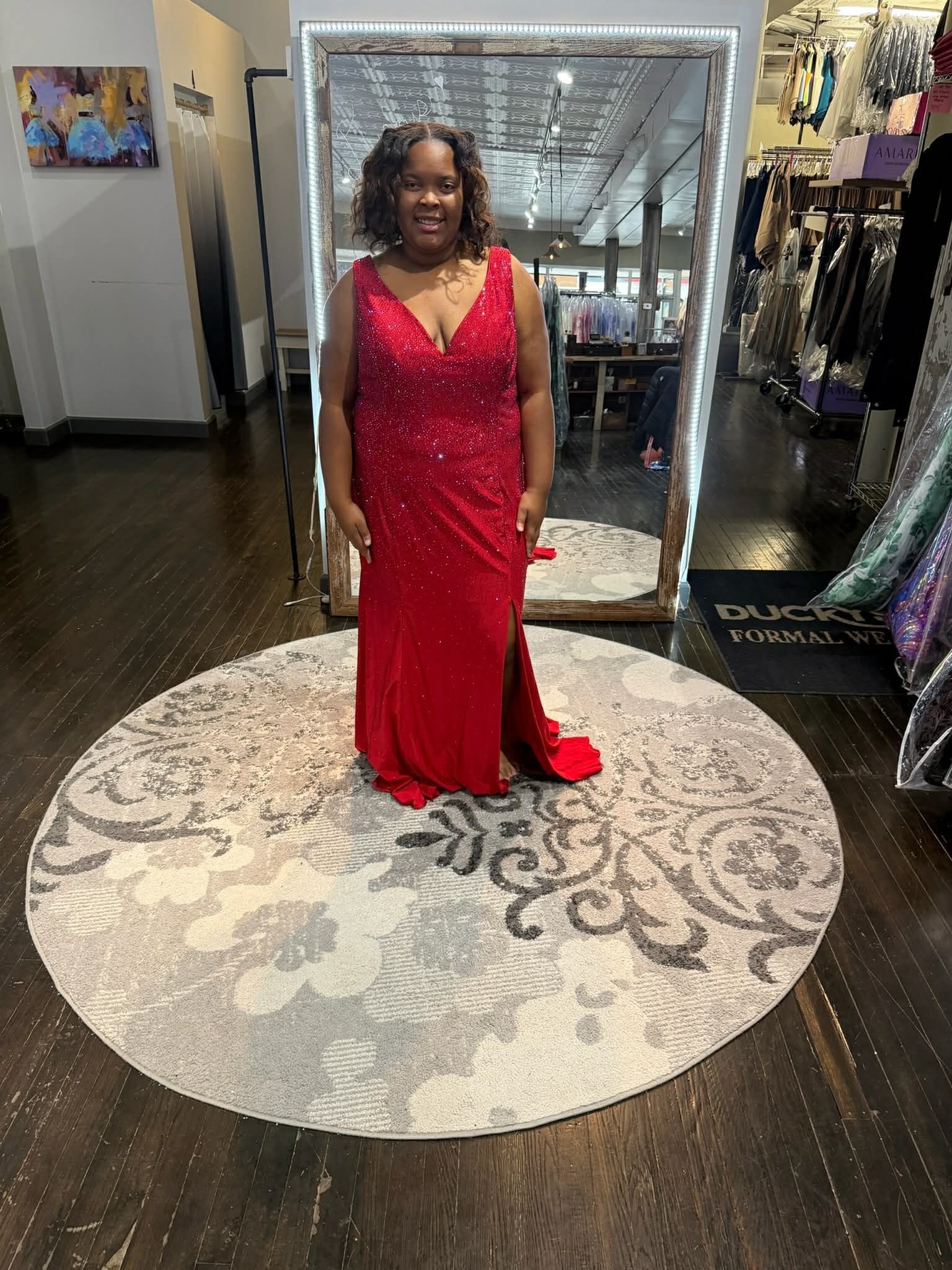 Five people pose in a boutique, wearing varying shades of green sequined floor-length evening gowns with side slits.