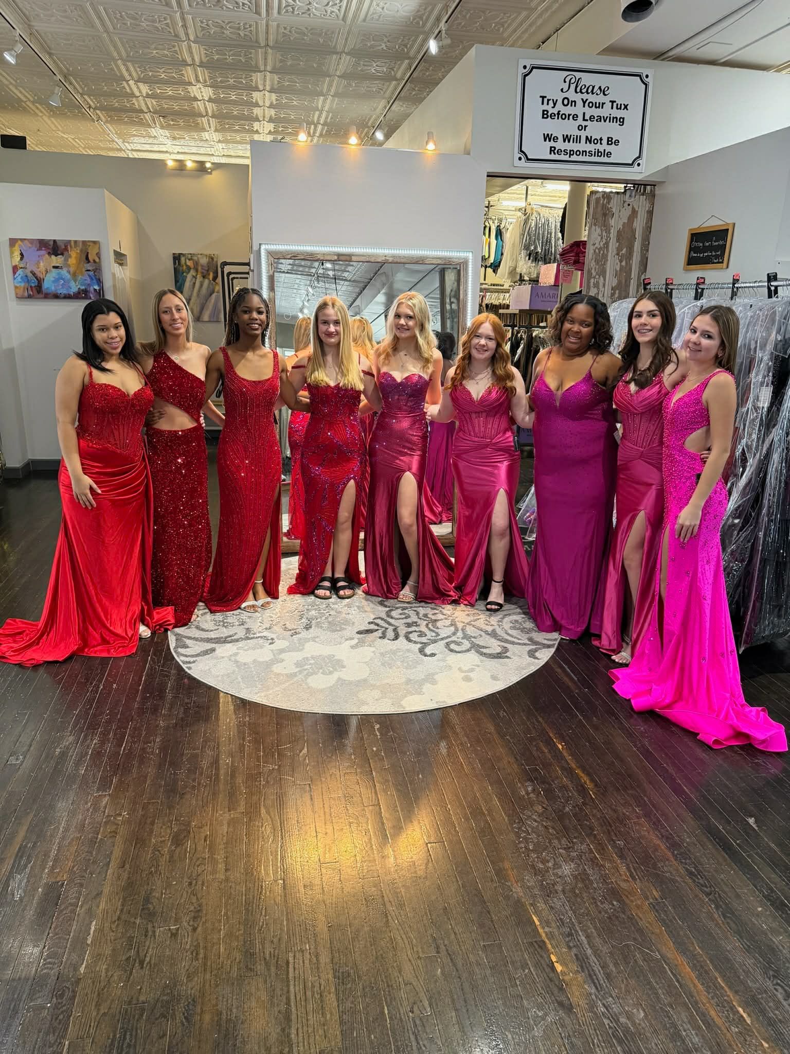 A person in a floor-length gold sequined gown with a low back stands on a round patterned rug in a clothing store.