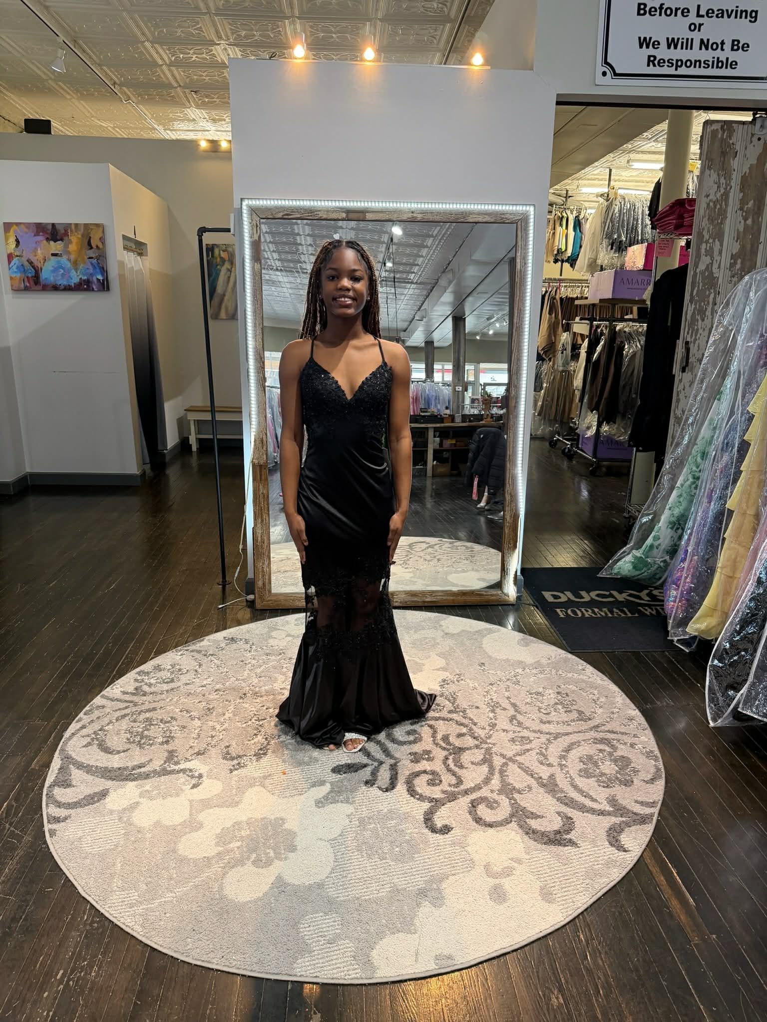 A person wearing a strapless, blue patterned gown with a tiered, ruffled skirt, standing in a formal wear boutique.