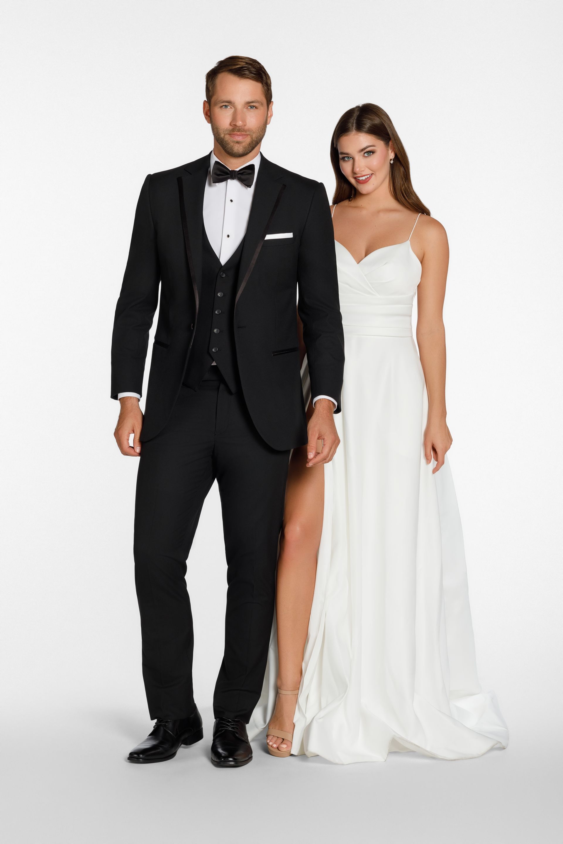 A man in a black tuxedo and a person in a white wedding gown stand side-by-side against a plain white background.