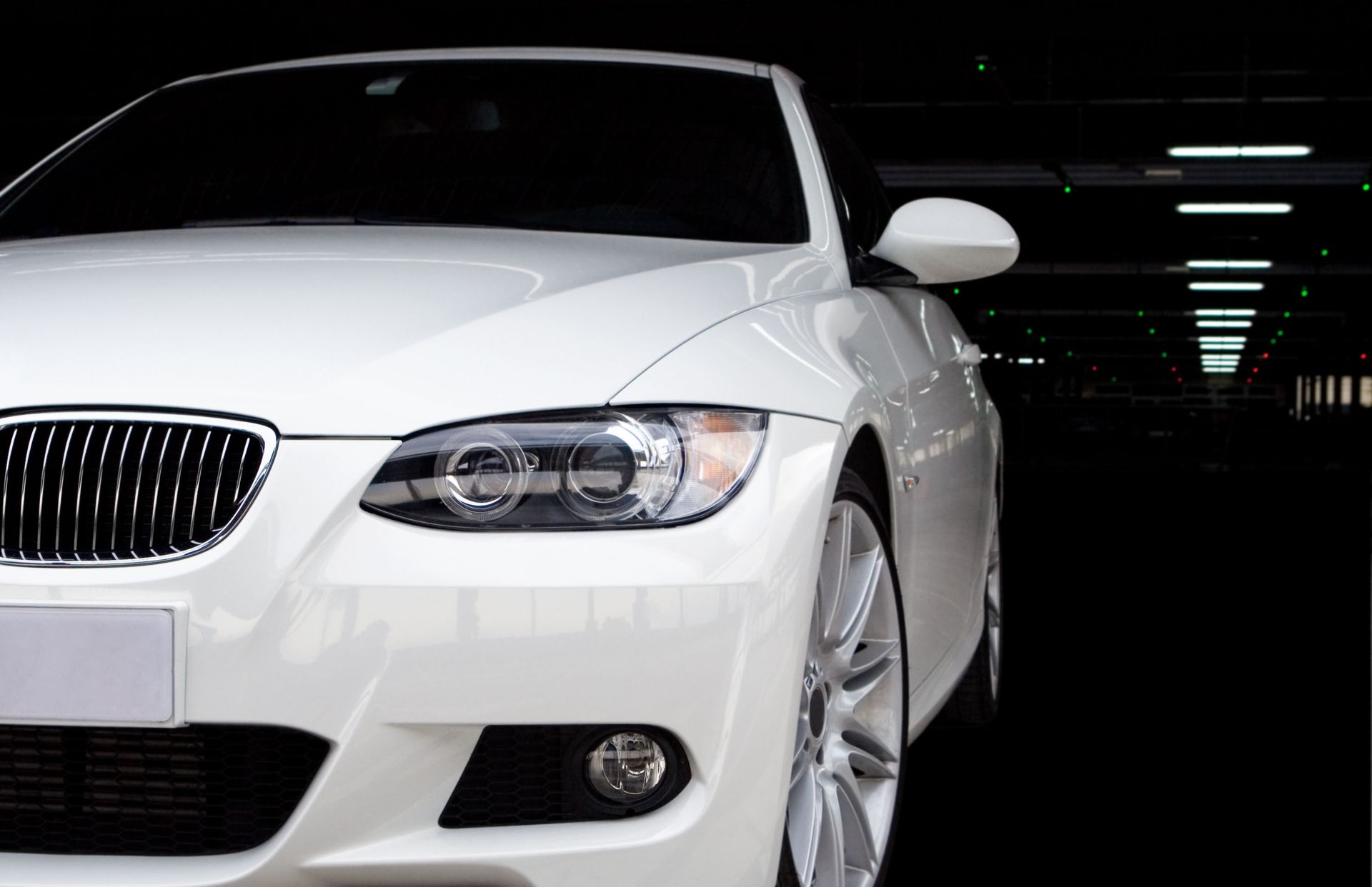 White BMW car parked in a dark parking garage.