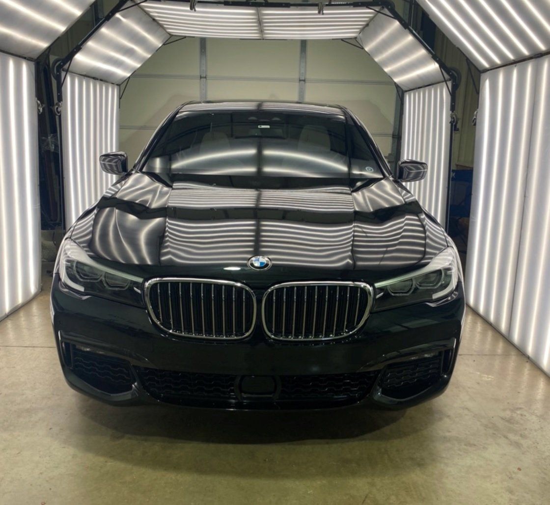 Black BMW sedan under bright white lights in a garage.