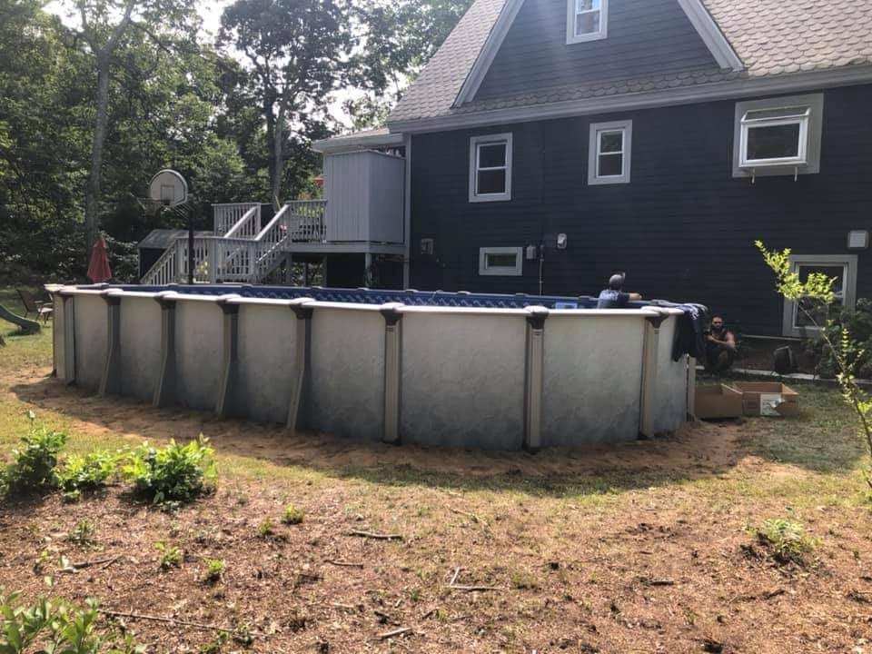 A large swimming pool is in the backyard of a house.