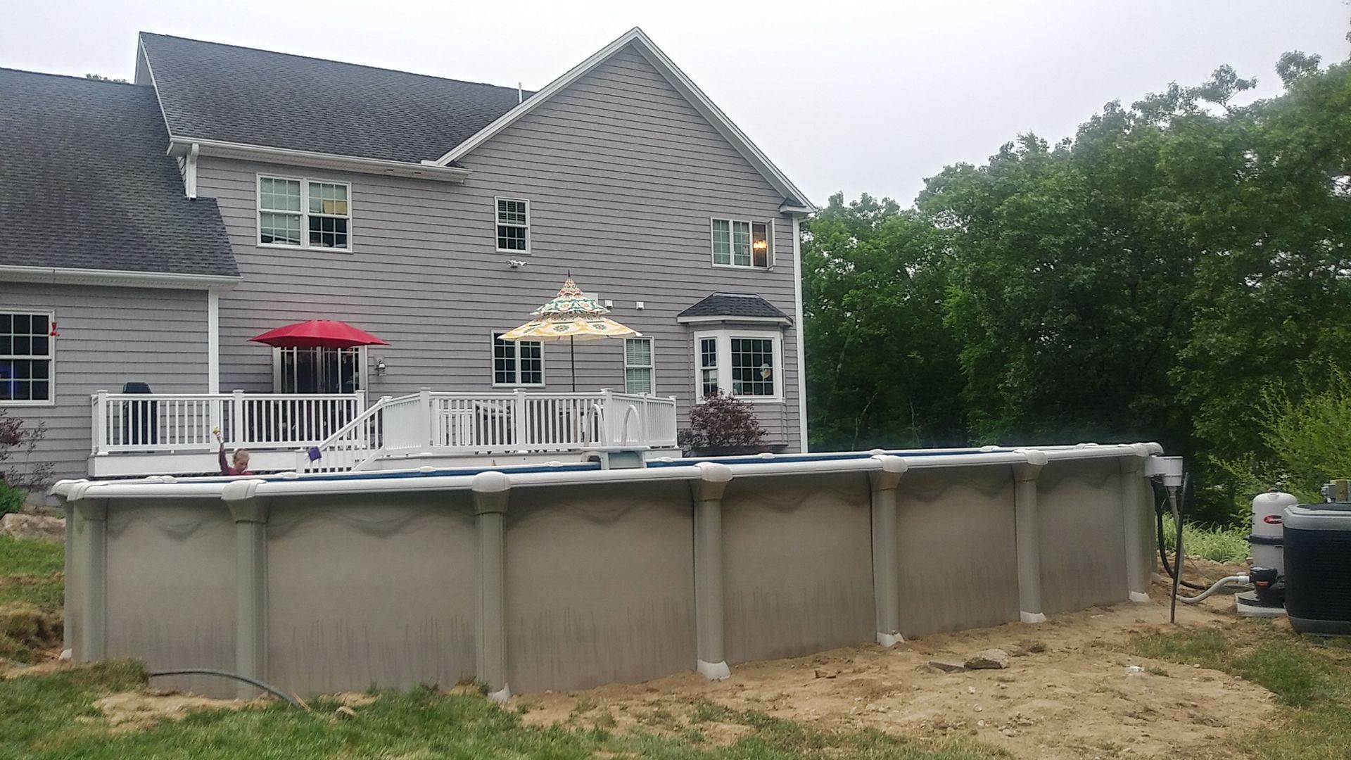 A large swimming pool is sitting in front of a large house.