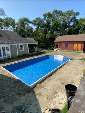 A large swimming pool is being built in the backyard of a house.