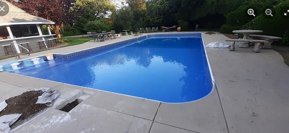 A large swimming pool with a picnic table in the backyard.