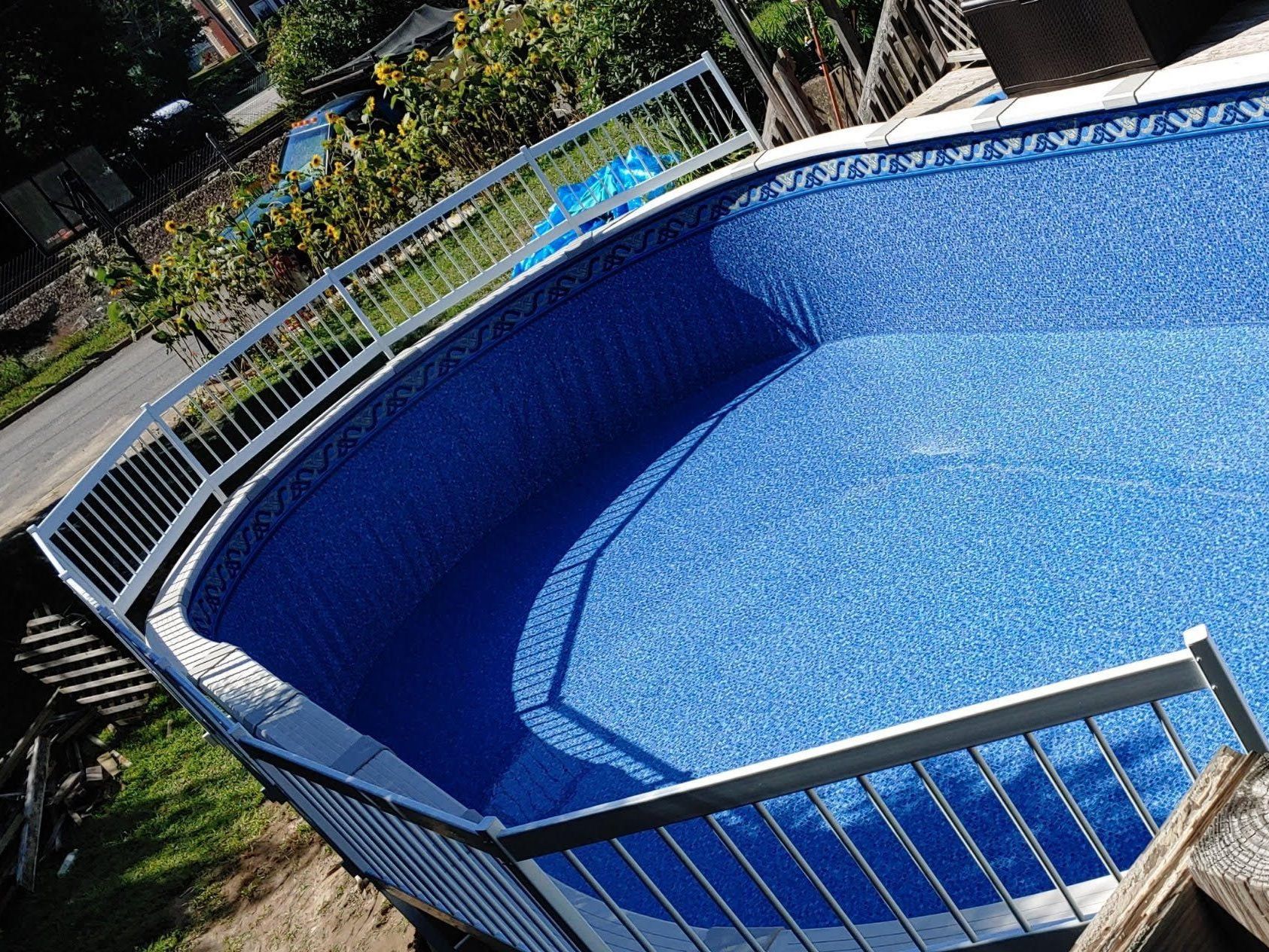 A large blue swimming pool with a metal railing around it.