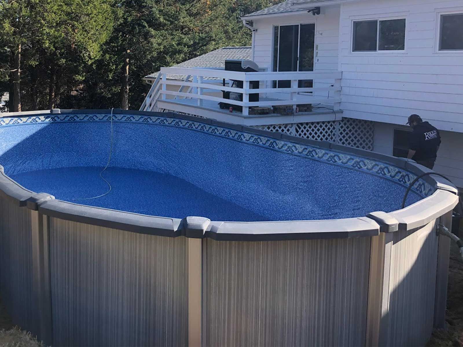 A large swimming pool is sitting in front of a house.