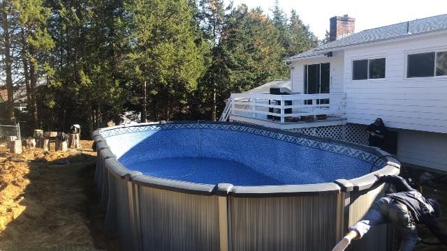 A large swimming pool is sitting in front of a house.