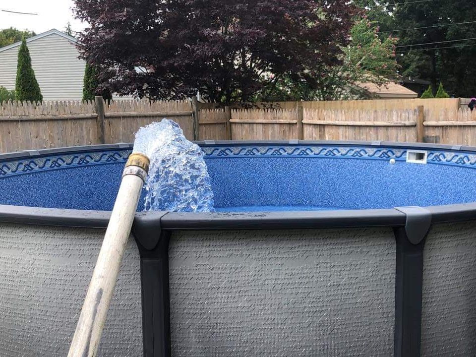 A hose is attached to the side of a swimming pool.