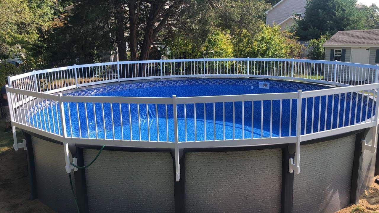 A large swimming pool with a white fence around it.