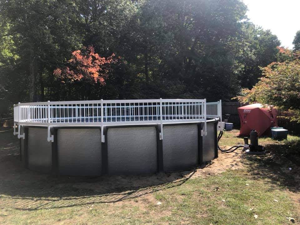A large swimming pool with a white railing in the backyard.