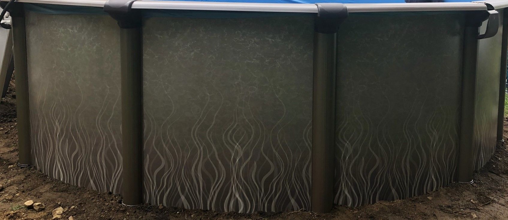 A large swimming pool is sitting in the dirt.