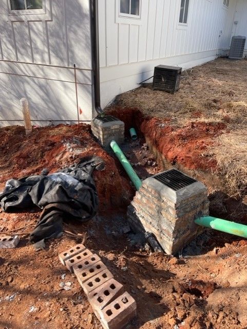 a pile of bricks sits in the dirt in front of a house