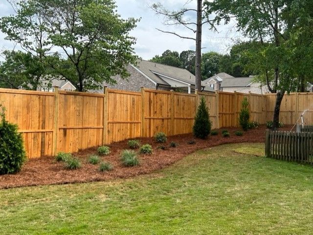 a wooden fence surrounds a lush green lawn in a backyard