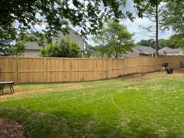 a wooden fence surrounds a lush green lawn in a backyard