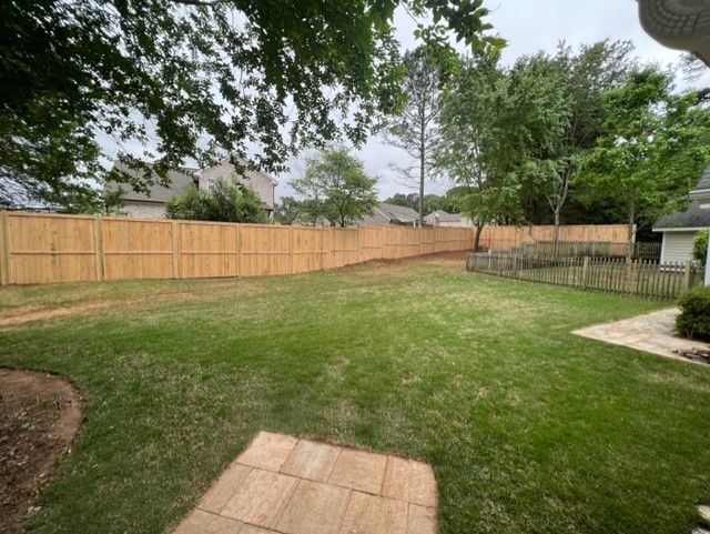 a backyard with a wooden fence and a lush green lawn