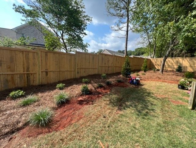 a wooden fence surrounds a backyard filled with plants and trees